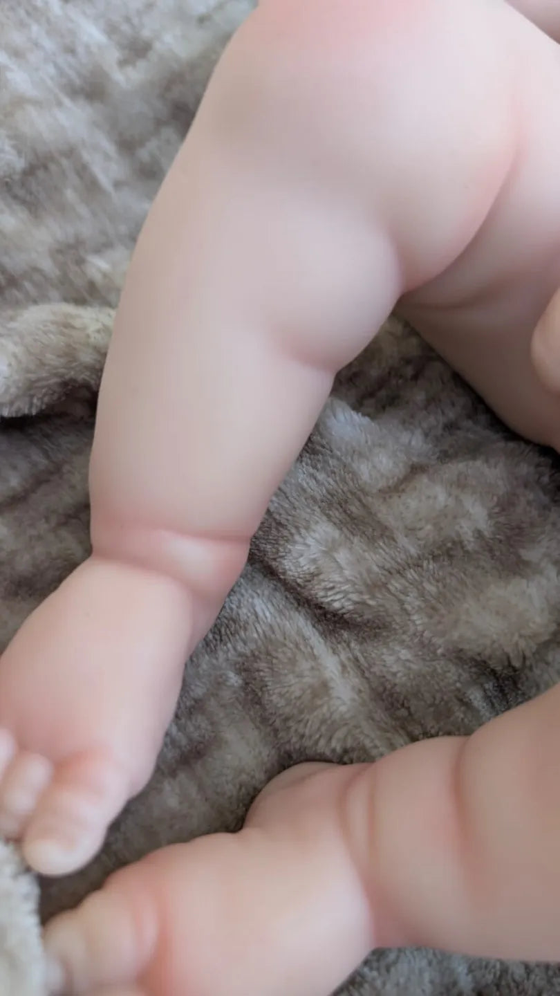 Pieghe realistiche delle due gambe del piccolo neonato reborn