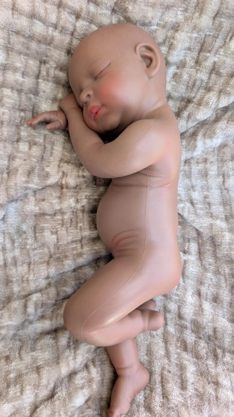 Bambola reborn africana 45 cm in posizione naturale da neonato con una gamba piegata