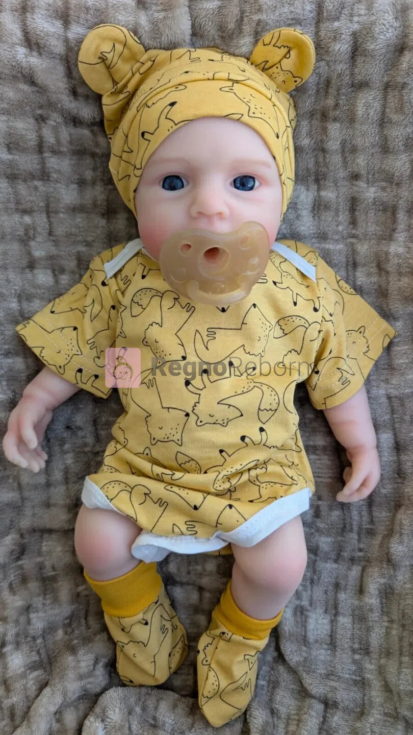 bambola reborn con vestiti da neonato gialli e ciuccio nella bocca