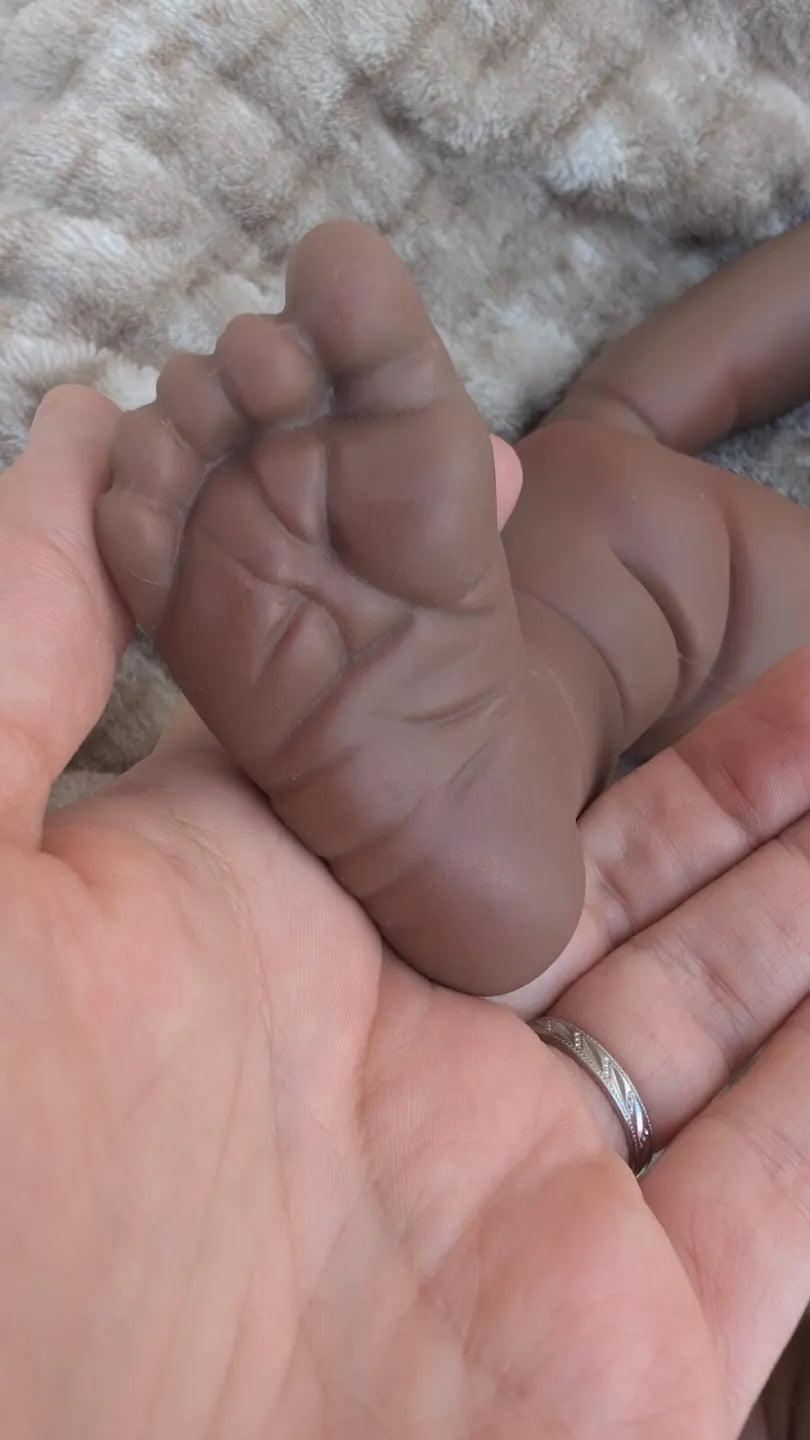 Bambola reborn nera realistica con dettaglio del piede