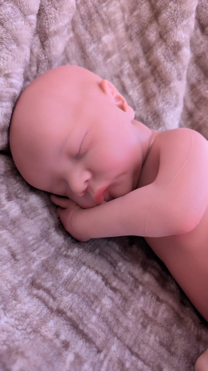 neonato reborn di 45cm in posizione da neonato appena nato e con il mano sotto la testa