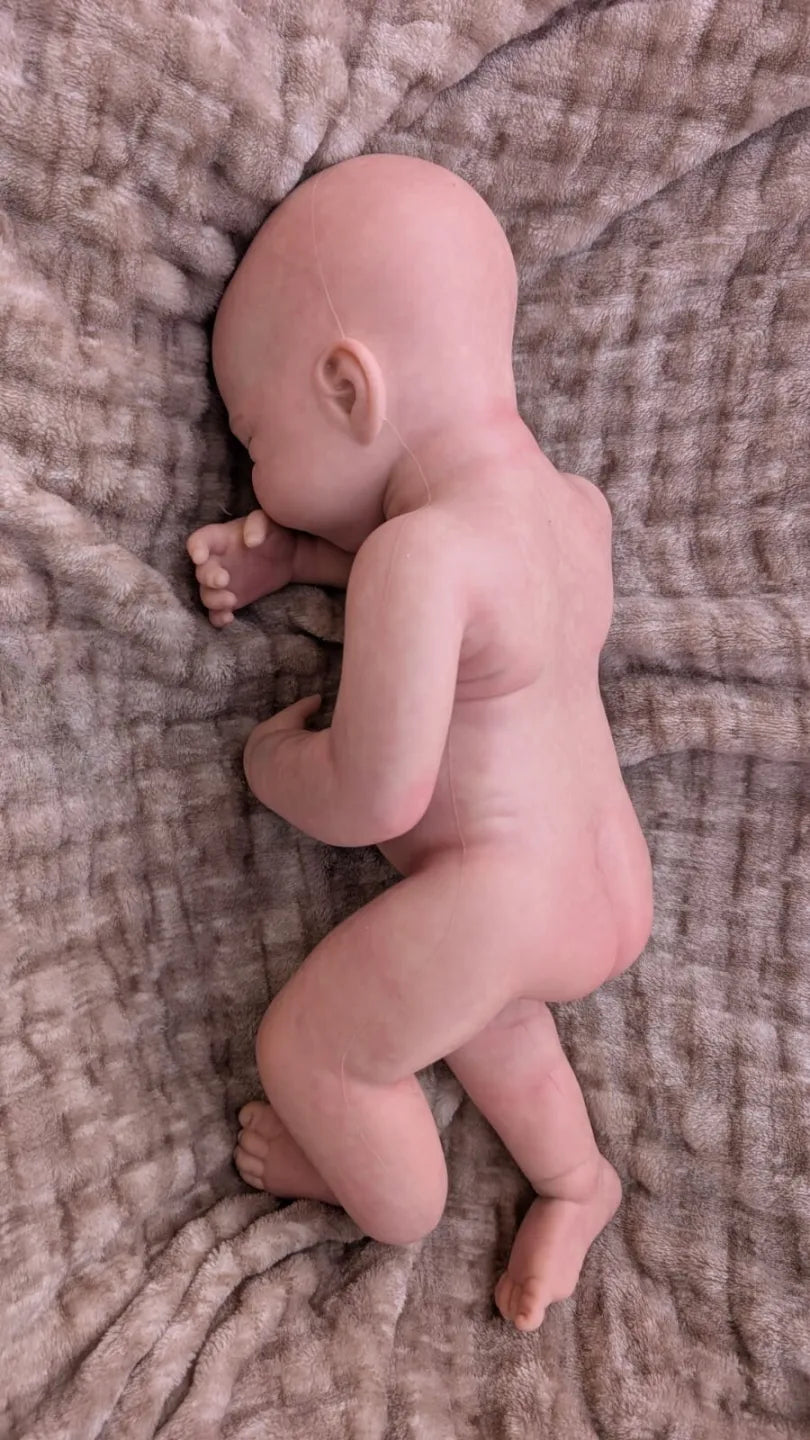 Neonata reborn che sembra vera in una naturale posizione da appena nata