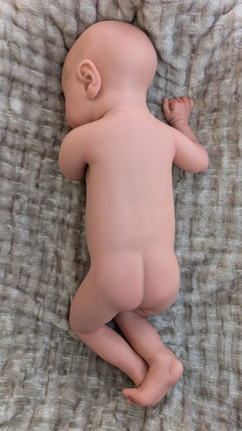 bambola reborn maschile in silicone intero nuda che sembra vista di dorso e con le gambe piegate