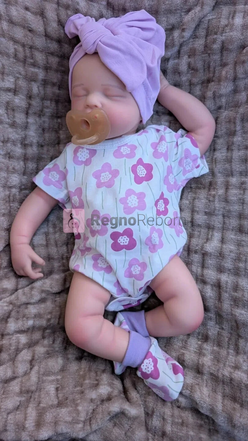bambola-reborn-con-vestiti da neonato e che sembra un bambino vero con il suo ciuccio nella bocca