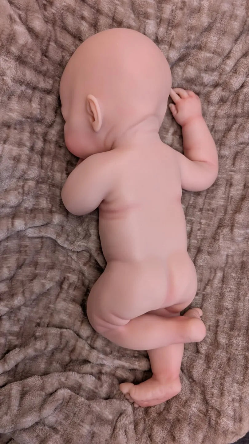 Grosso bimbo reborn con rotolini di grasso sulle gambe piegate vista posteriore