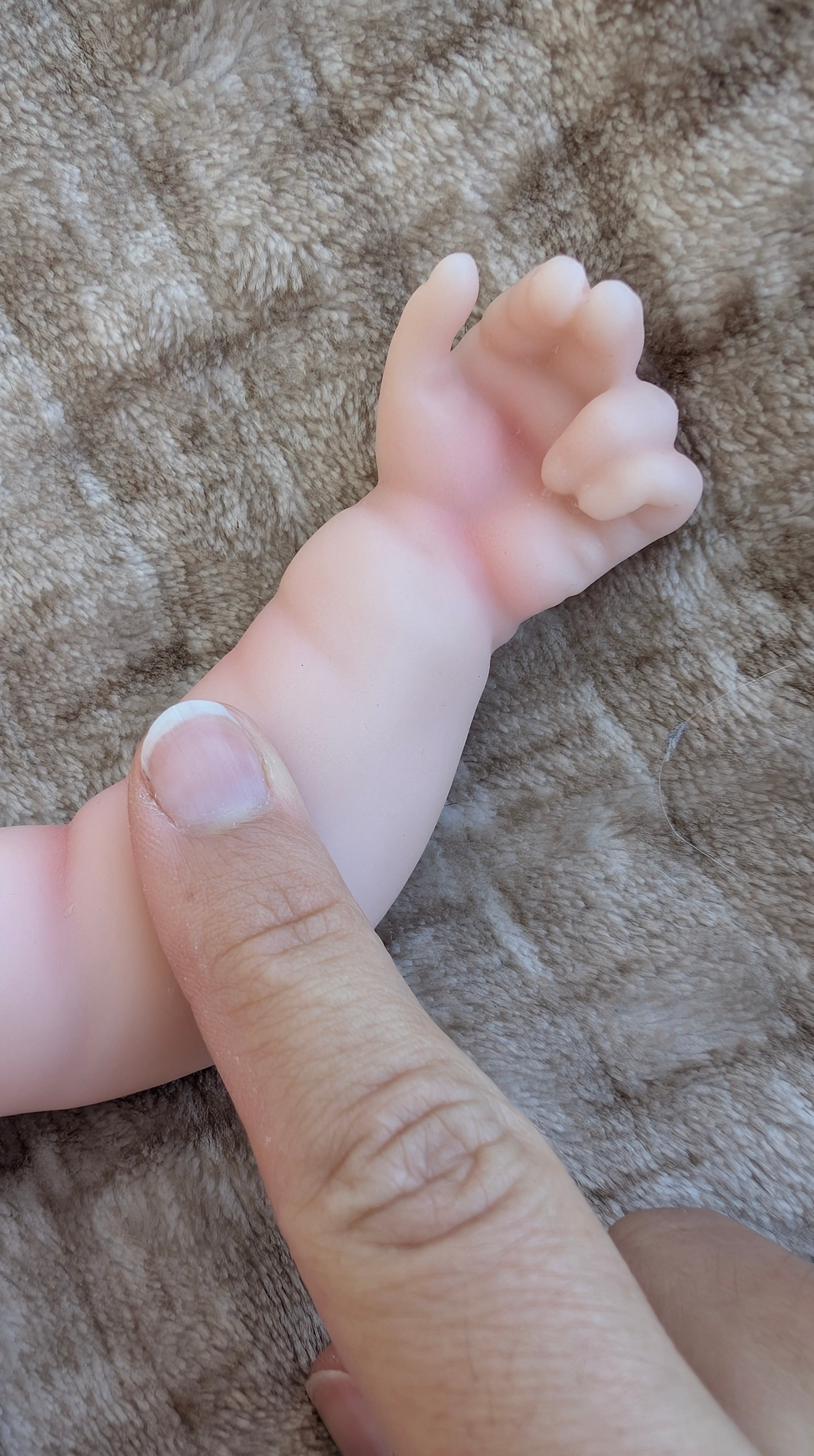 Mano e pieghe del polso di un bambolotto reborn prematuro in silicone