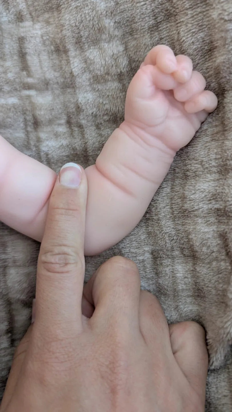Braccio flessibile della bambola reborn che mostra la morbidezza del silicone e gli dettagli realistici della mano