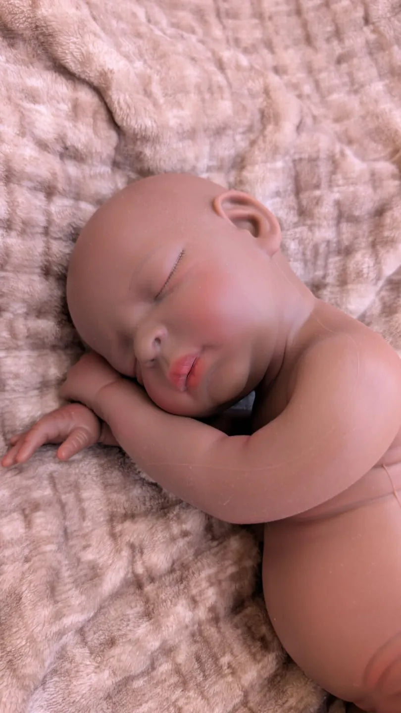 Neonata reborn africana in una naturale posizione da bambina appena nata